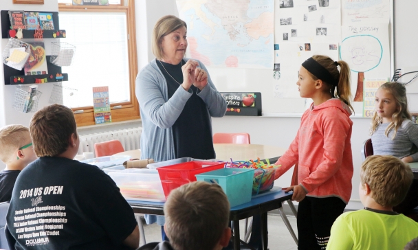 Sue stands, looking at her students expectantly in the classroom.