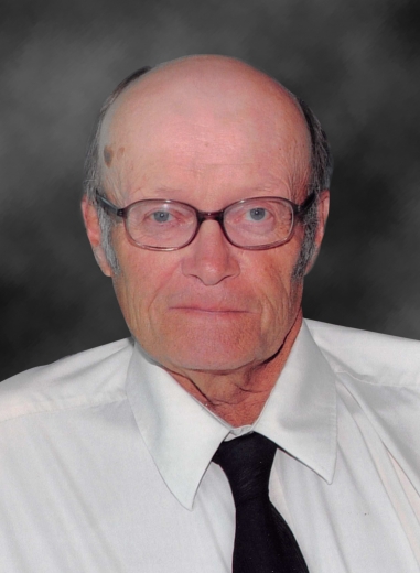 Doug Pennings sits for a photo. He wears glasses, a button-up, and black tie.