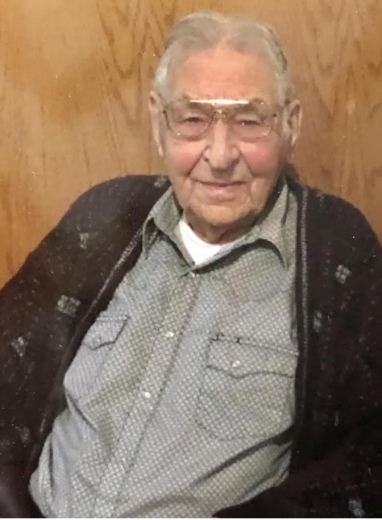 Otto Boehm smiles, relaxed. He wears a button-up and cardigan.