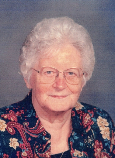 Arlene Karels smiles gently at the camera. She wears a floral and paisley blouse.